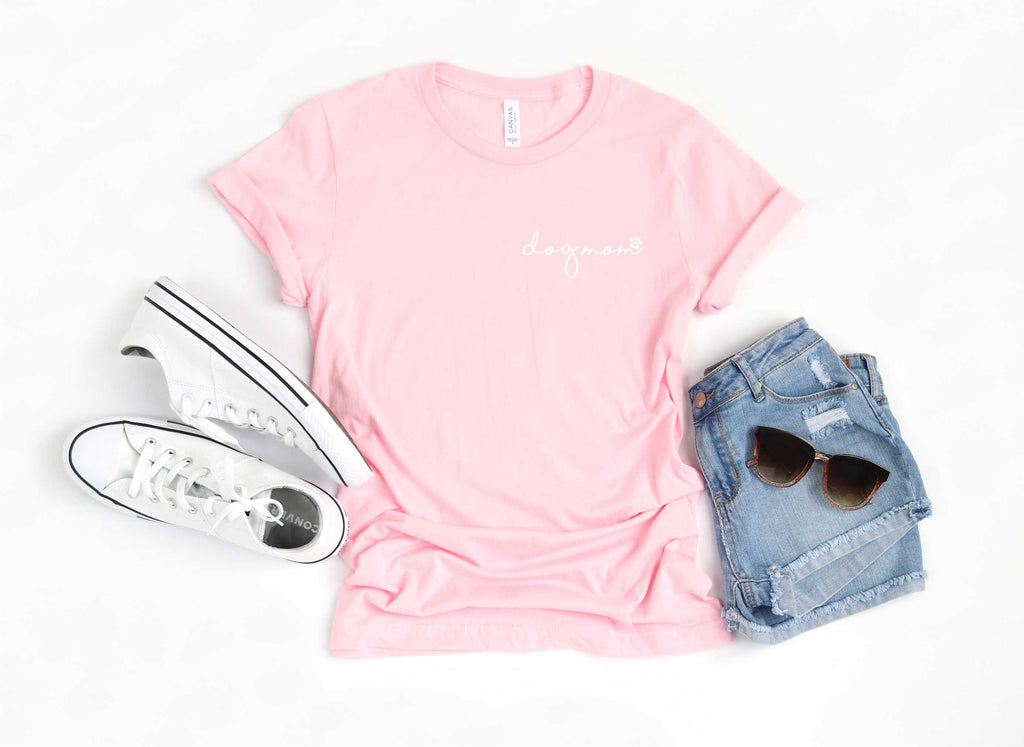 pink  short sleeve tshirt printed with dog mom in lower case script writing with a little paw print in white ink placed over the left chest