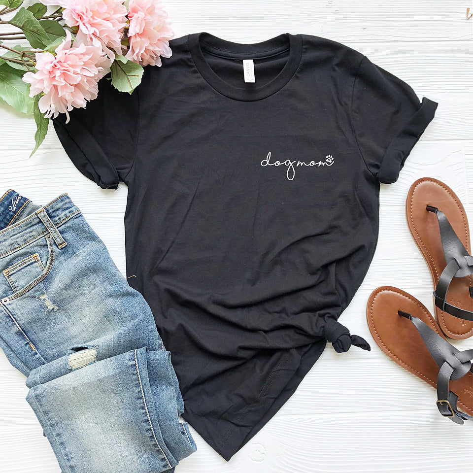 black  short sleeve tshirt printed with dog mom in lower case script writing with a little paw print in white ink placed over the left chest