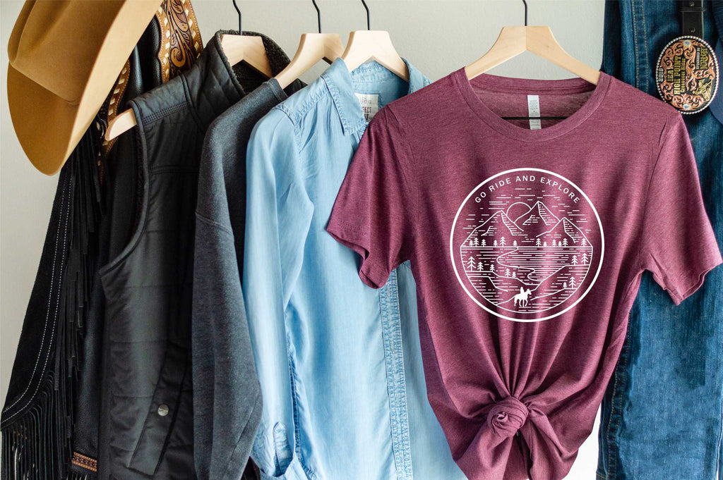 maroon short sleeve tshirt printed with a mountain scene and a silhouette horse and rider with the saying Go Ride and Explore arched across the top.