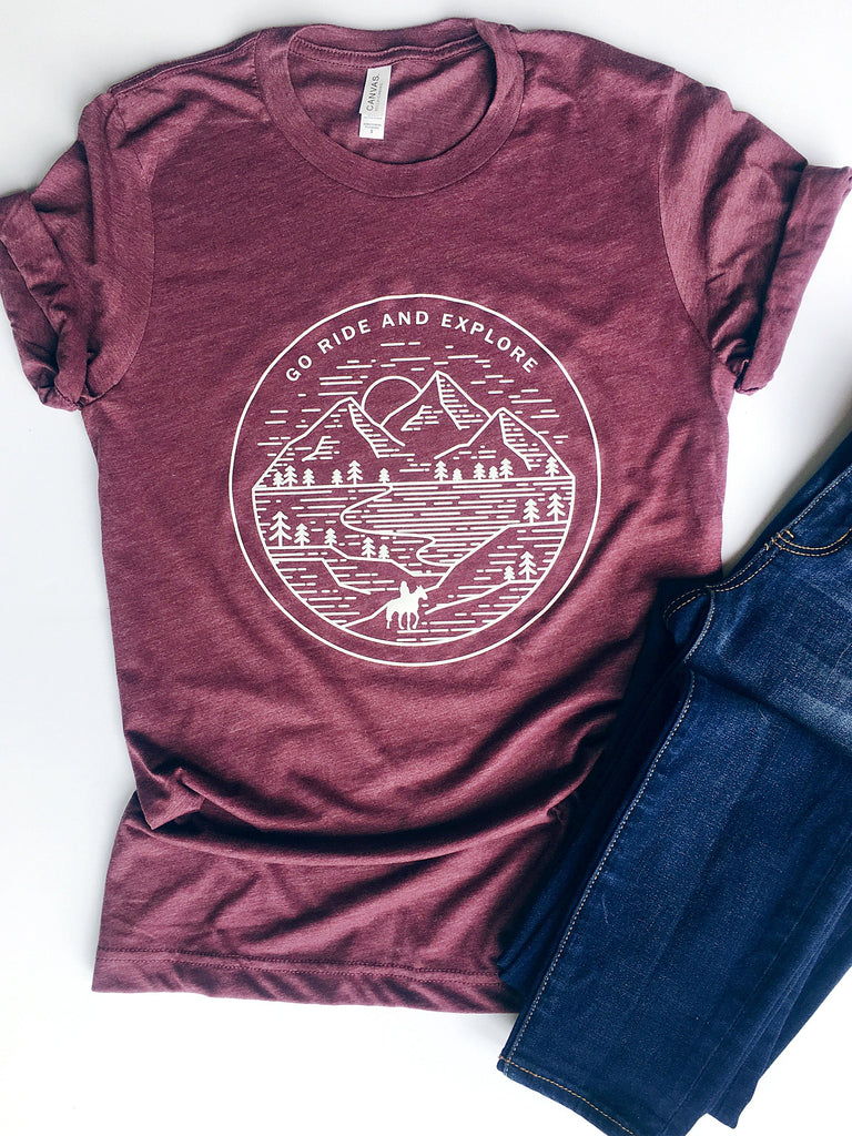 maroon short sleeve tshirt printed with a mountain scene and a silhouette horse and rider with the saying Go Ride and Explore arched across the top.